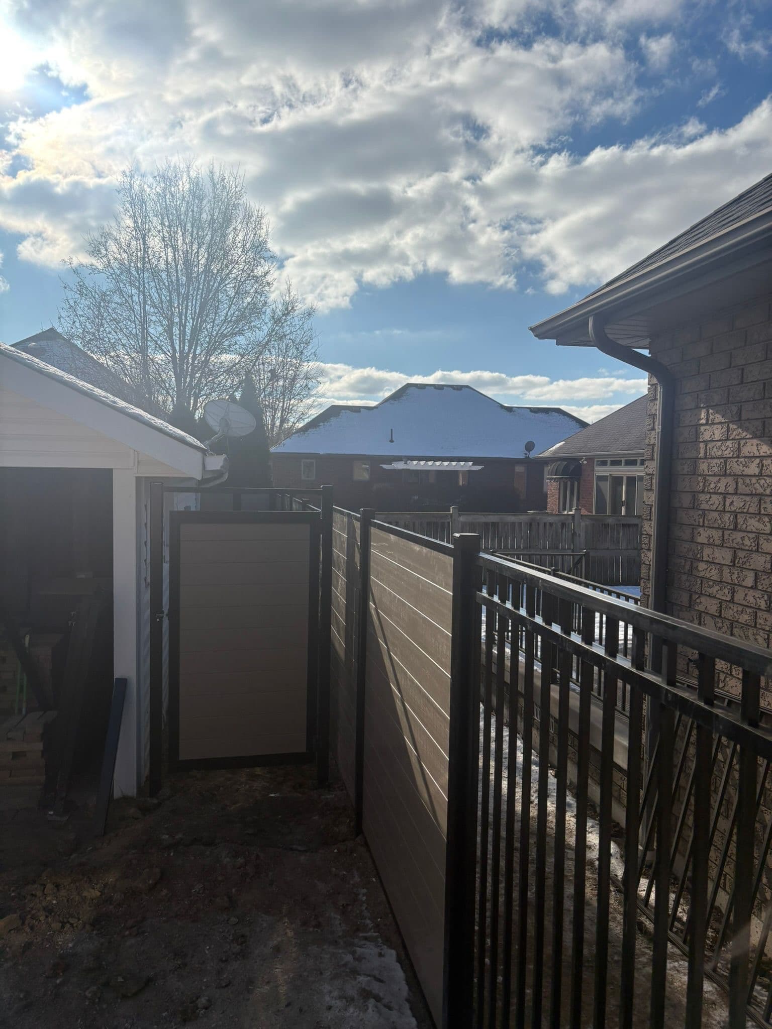 Tan and gray vinyl privacy fence in natural woodland setting