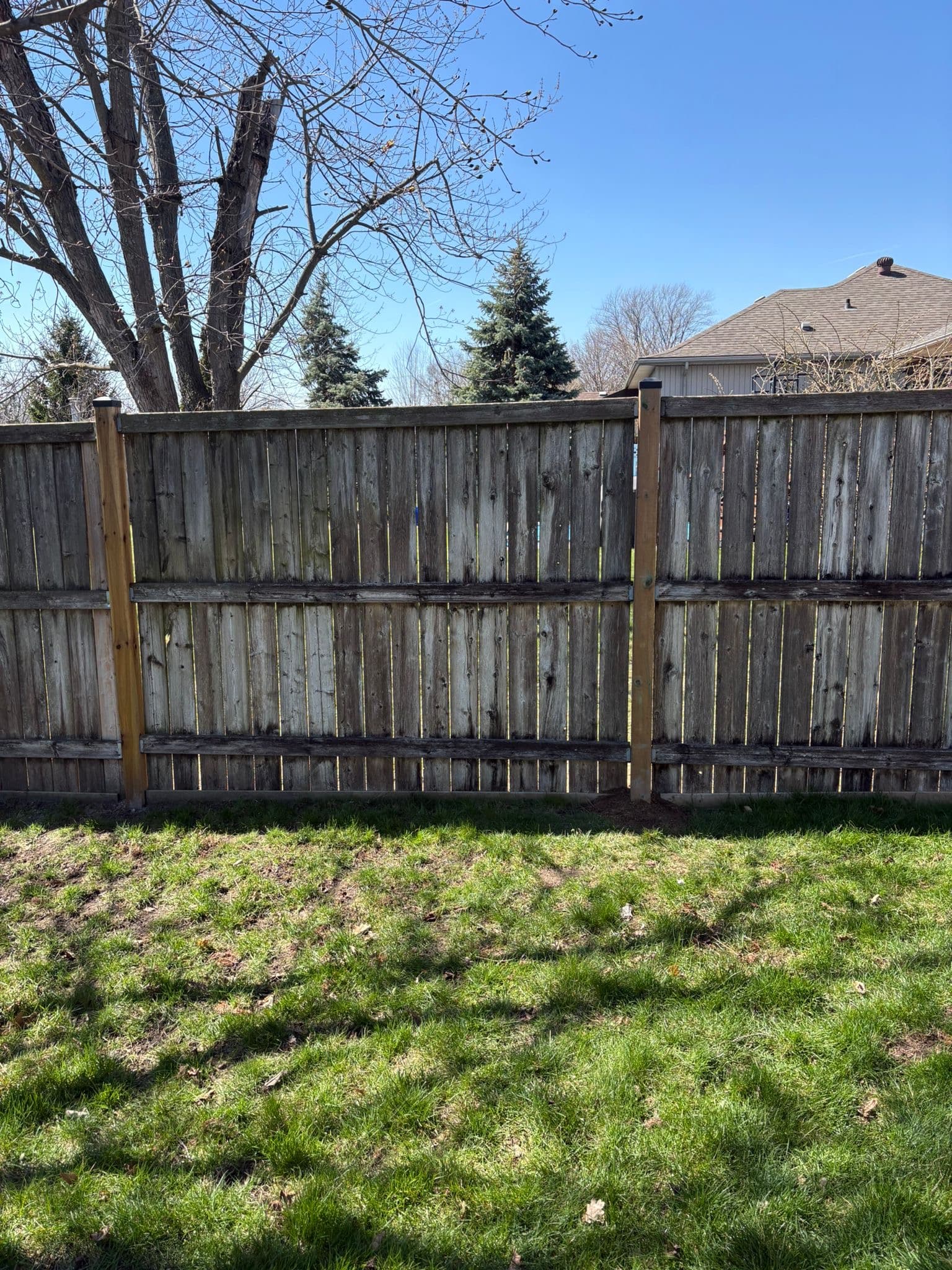 Multi-rail wood fence showing wear and restoration