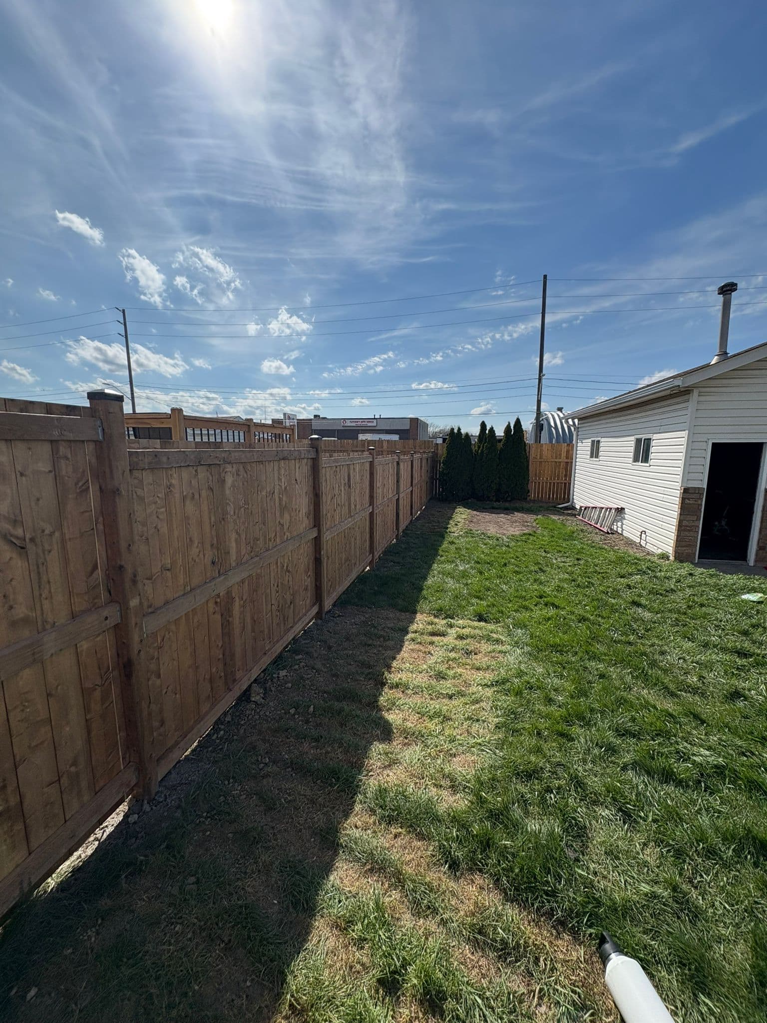 Long run of brown wood privacy fence with gate and landscaping