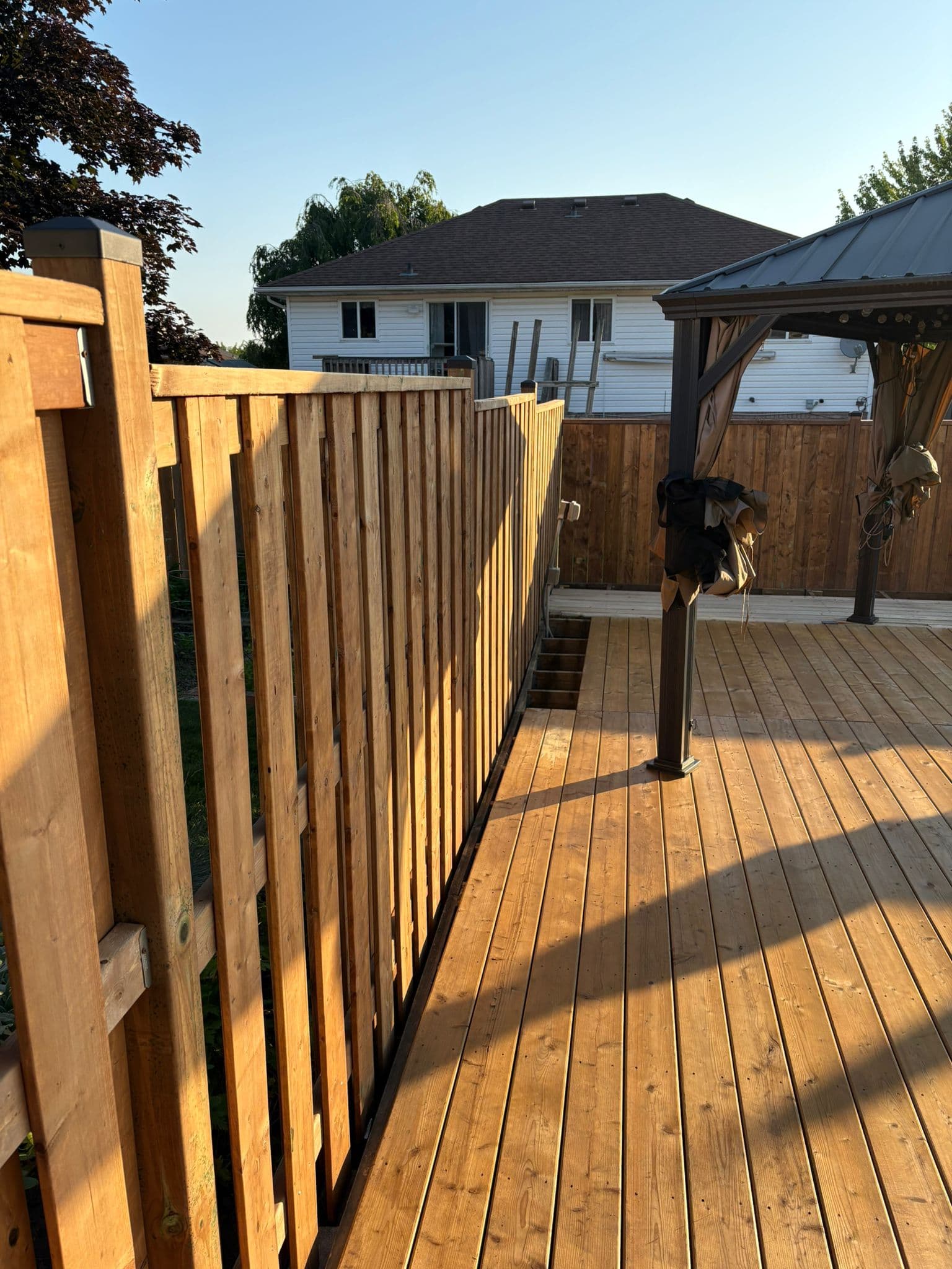 Rustic wooden deck with pergola and fence installation in backyard
