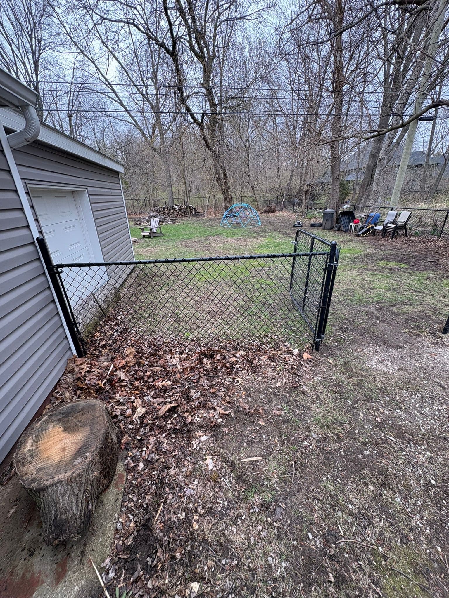 Black chain link fence gate in wooded area