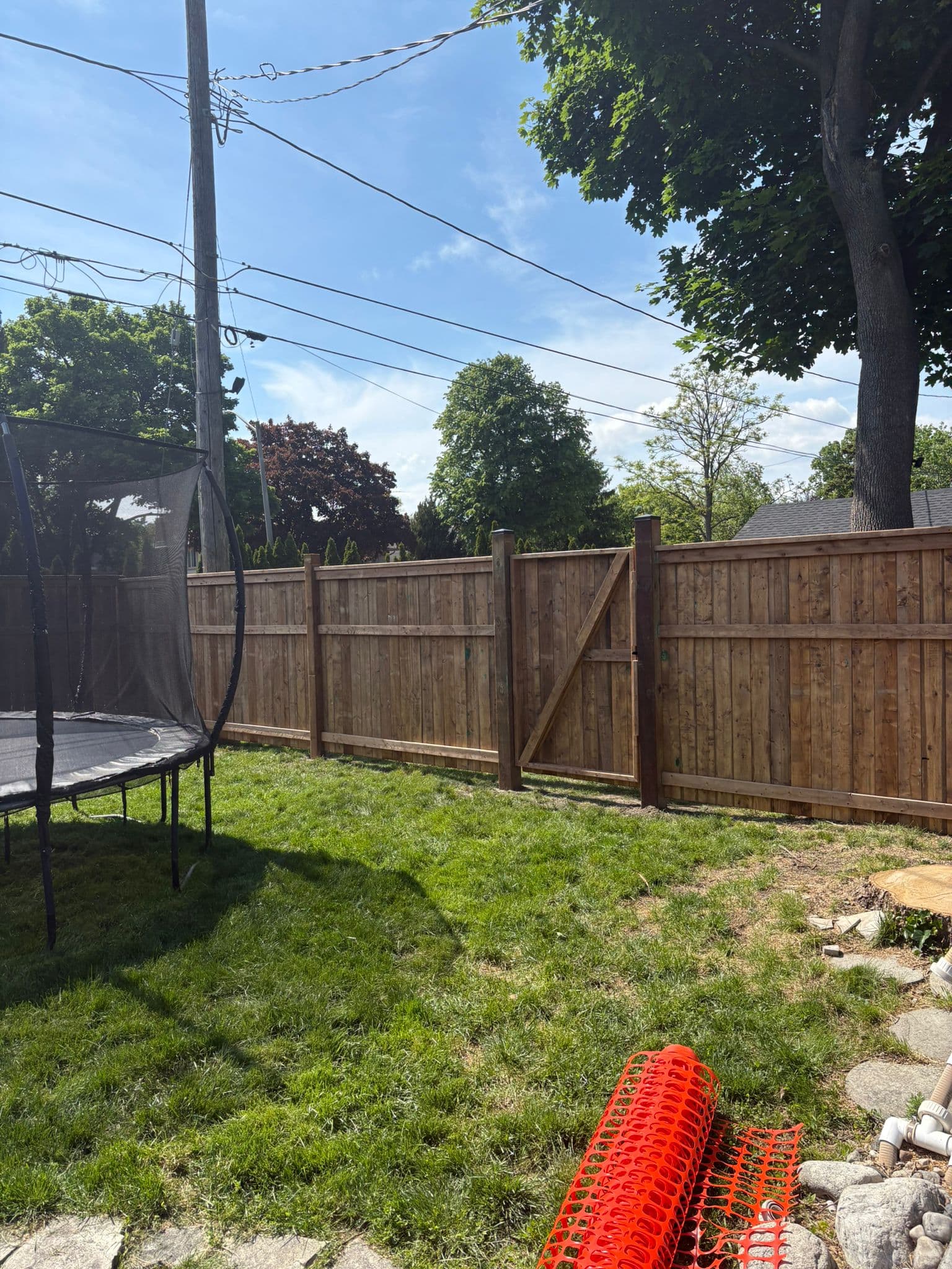 Brown wood fence with trampon in residential backyard