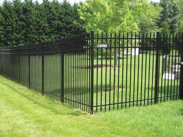 Black ornamental aluminum fence with gate in lush residential landscape