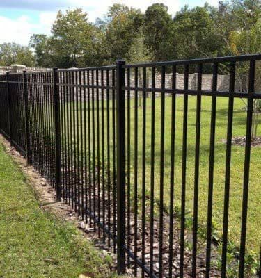 Black aluminum ornamental fence along property with trees