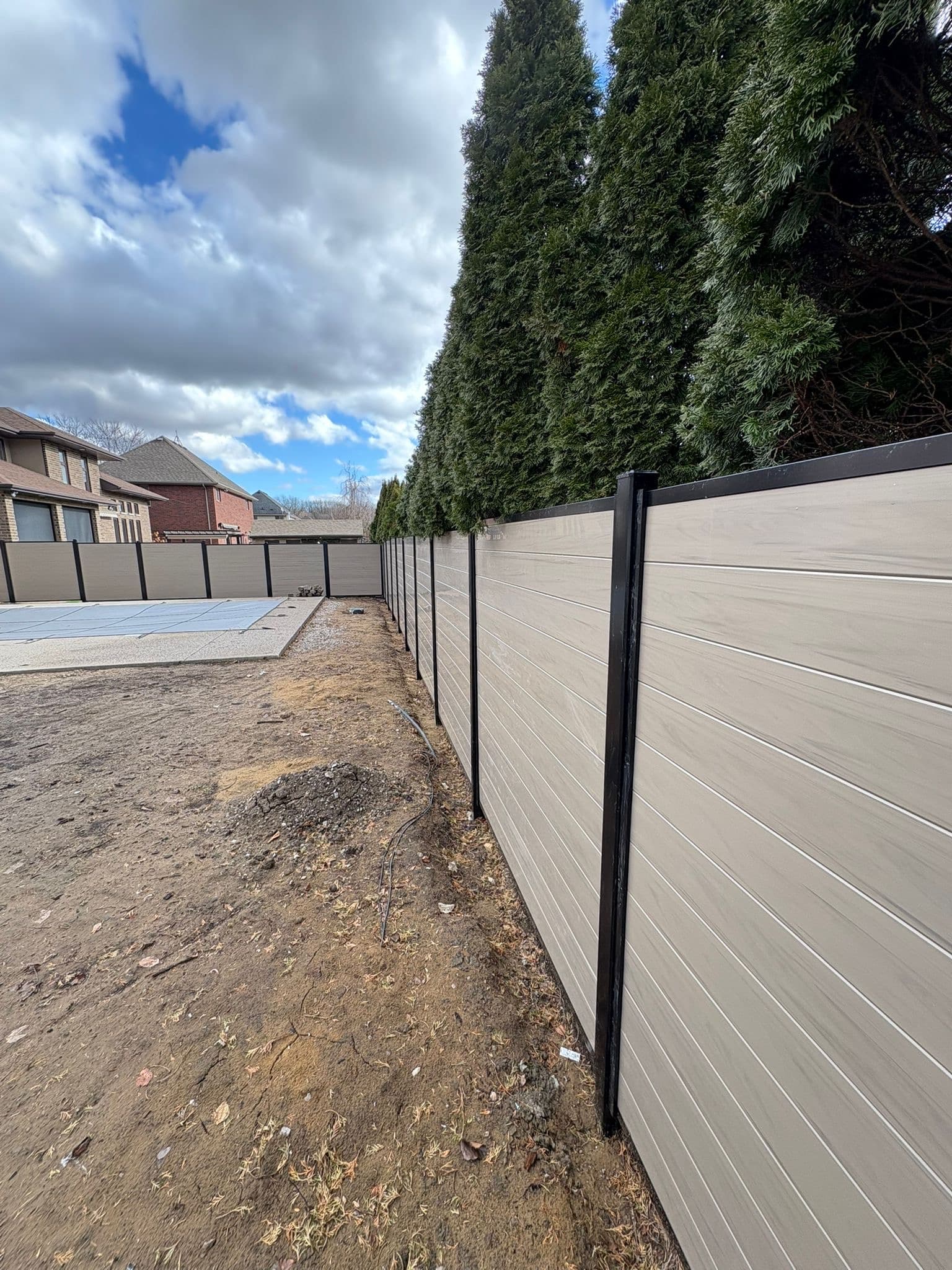 Tan vinyl privacy fence with rural property landscape
