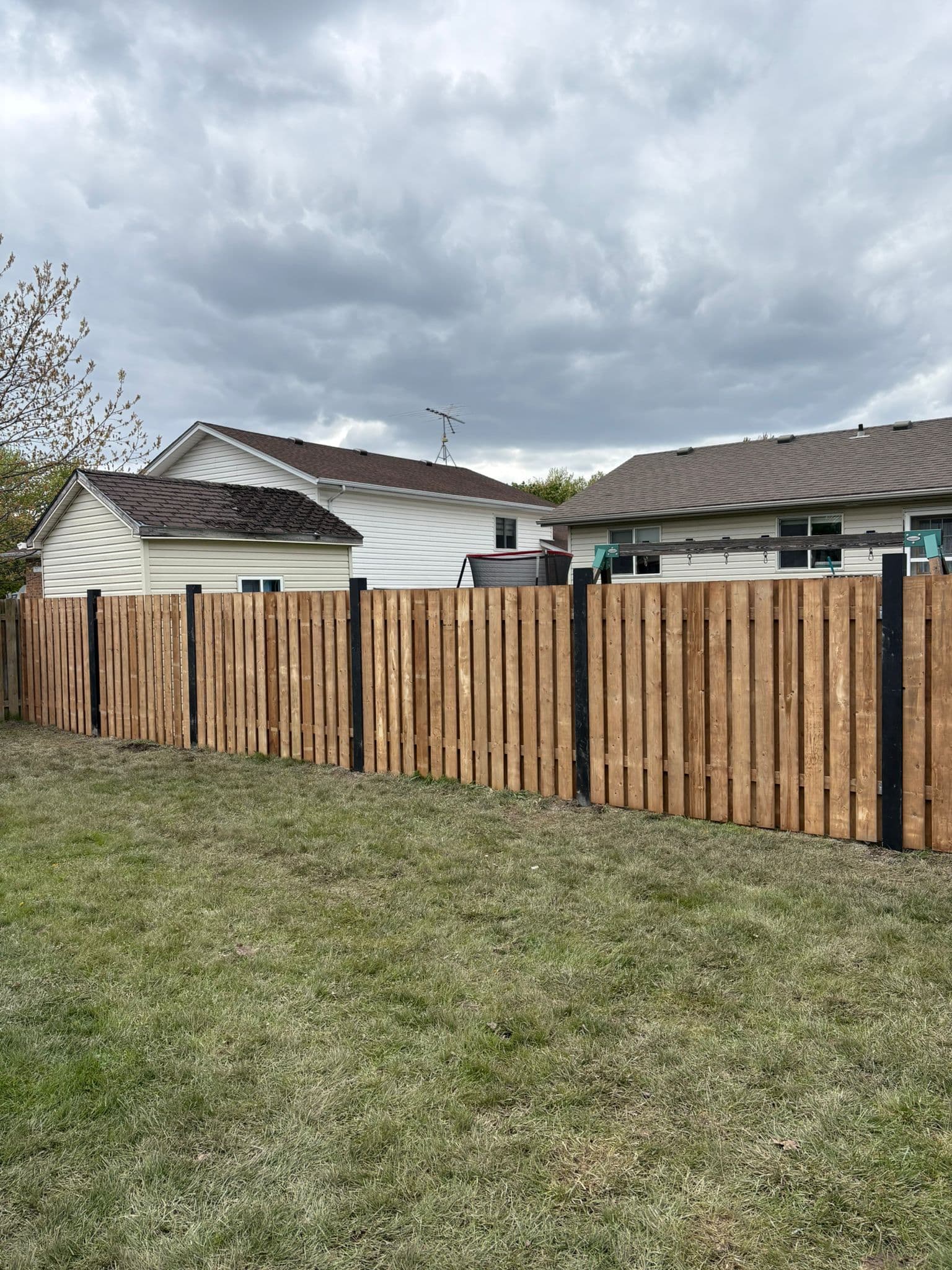 Wood fence along property with mature landscape and trees
