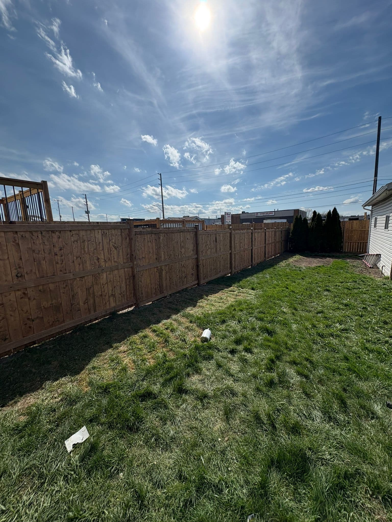 Brown wood fence with black posts in spacious backyard