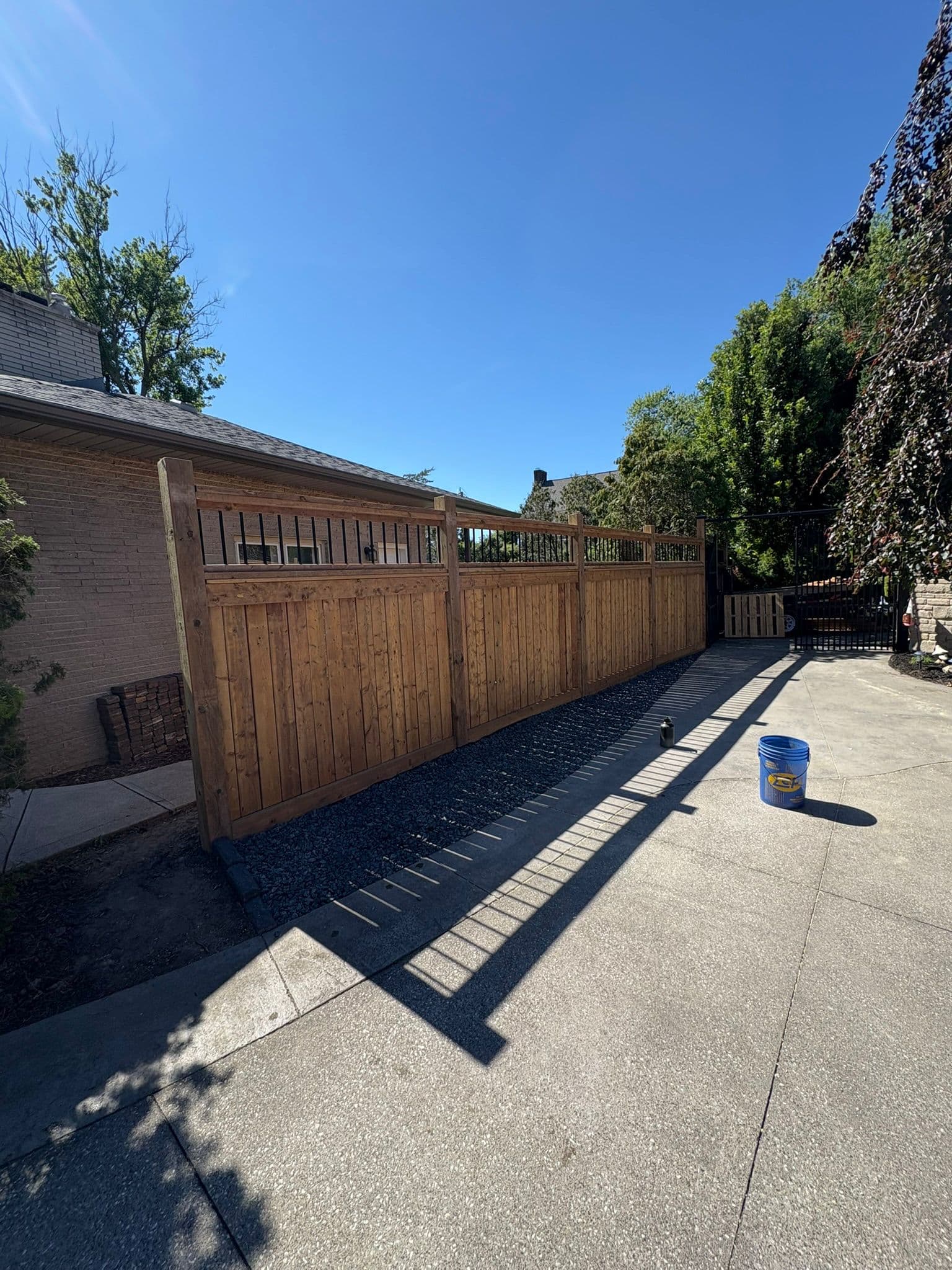Wood fence with gate and decorative top rail against brick home