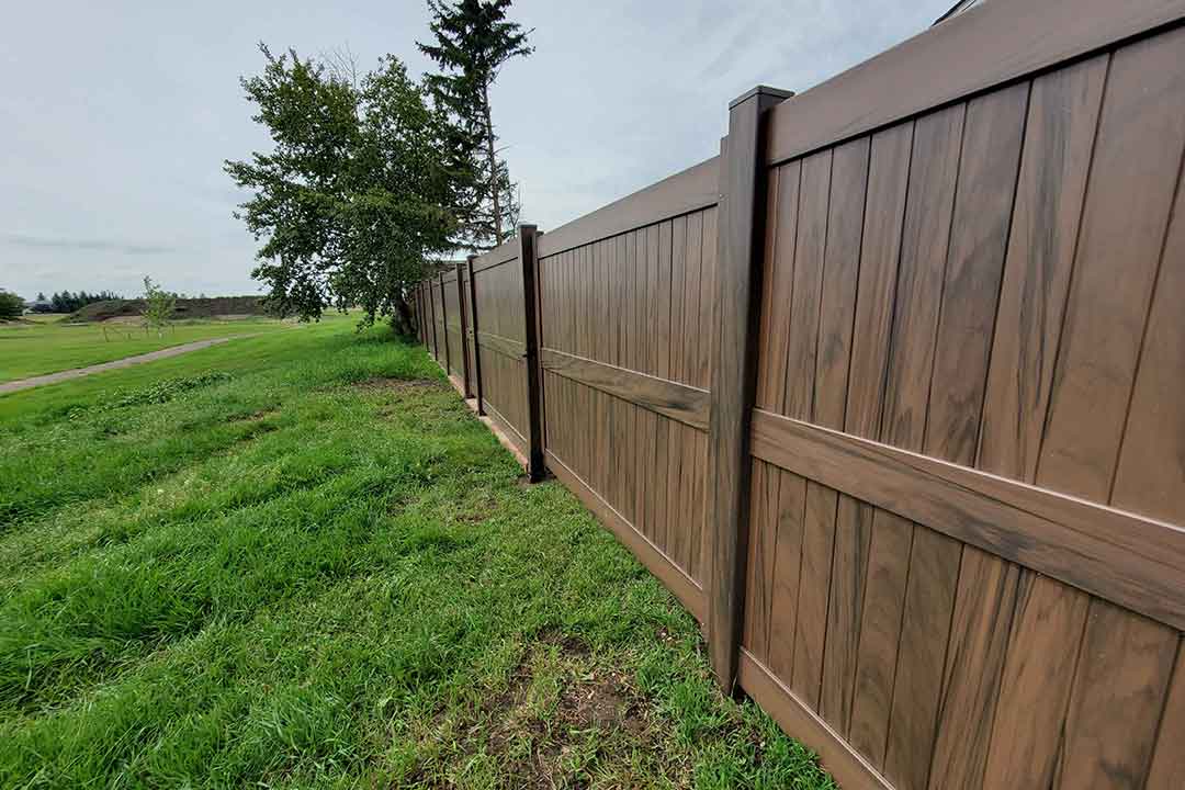 Tan vinyl privacy fence in agricultural property setting