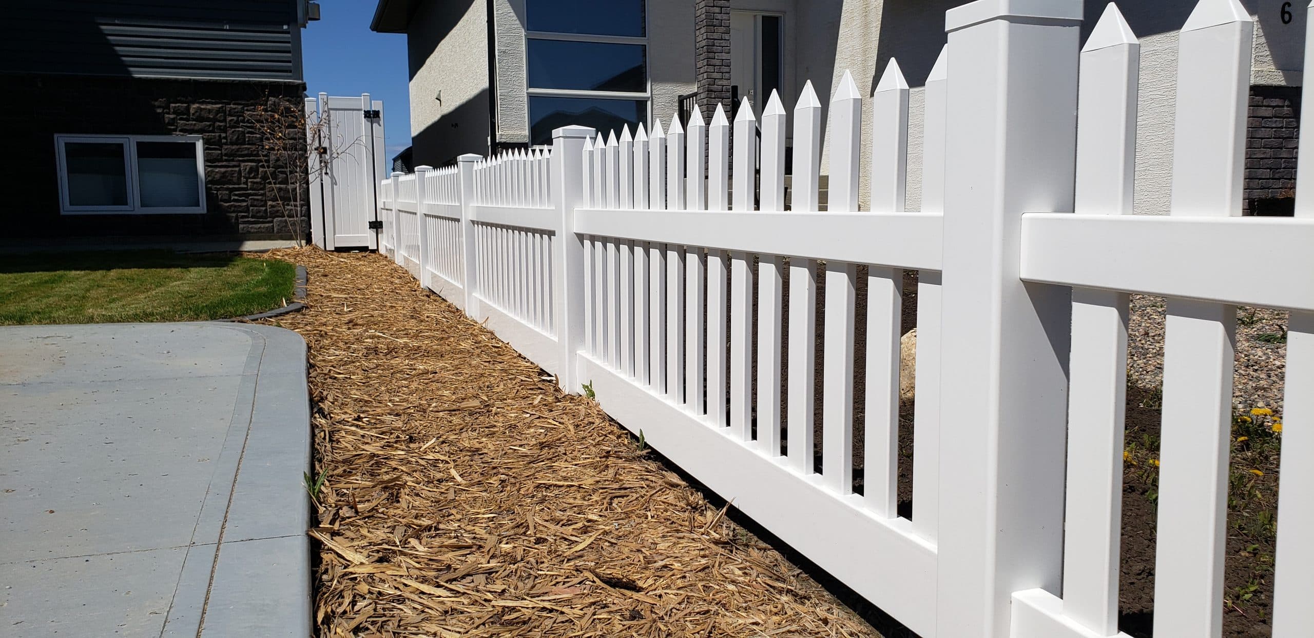 White vinyl picket fence with decorative cap gate in front yard