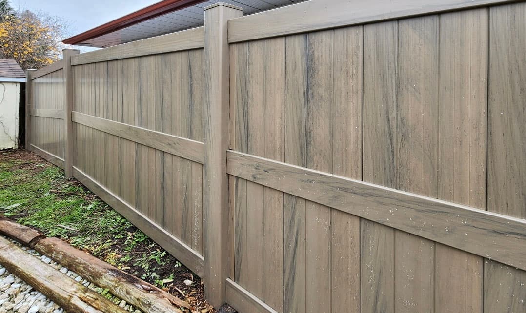 Gray wood grain textured vinyl privacy fence with horizontal rails