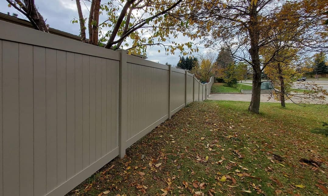 Tan vinyl privacy fence in natural landscape setting