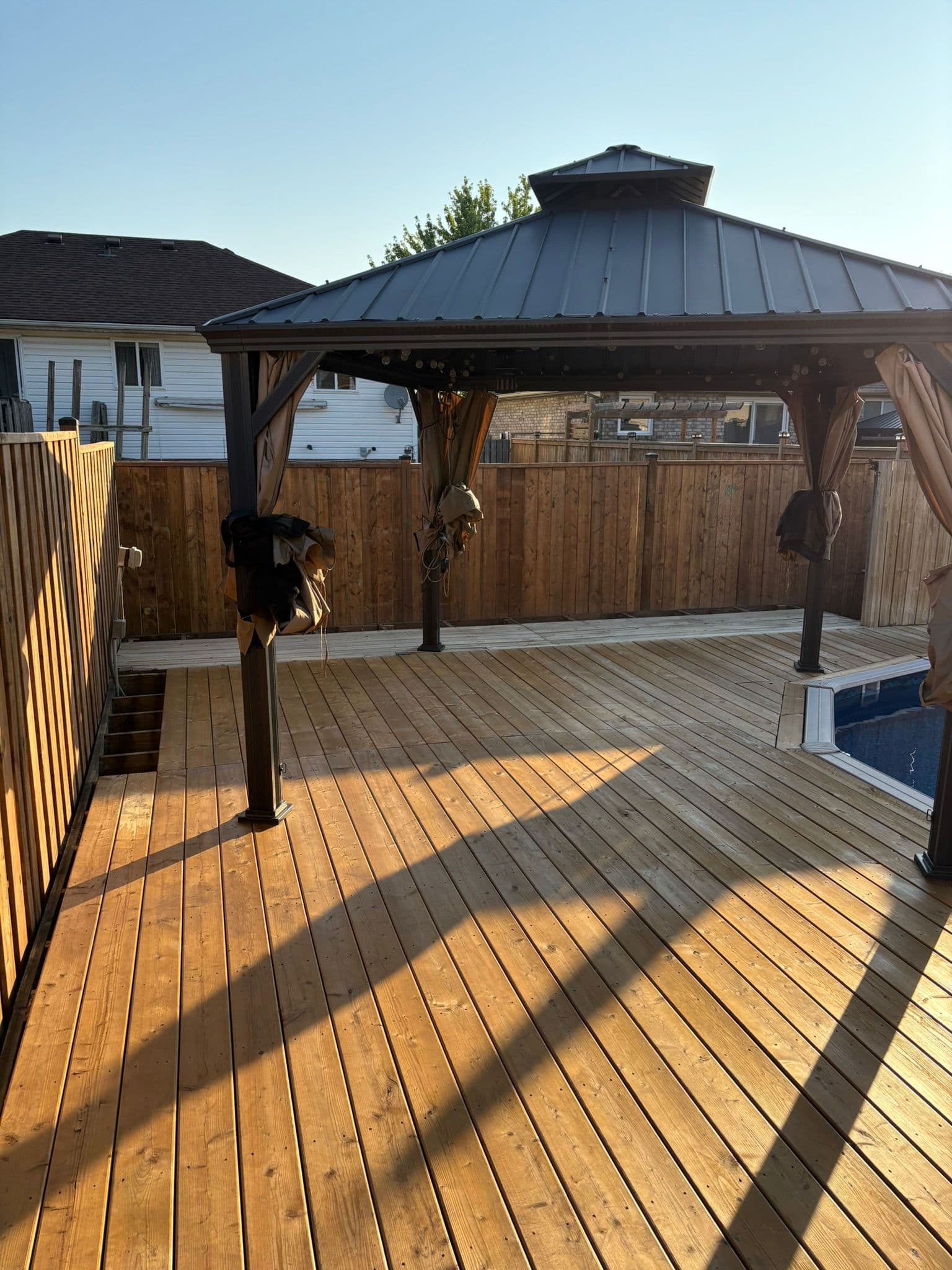 Beautiful wooden deck with pergola and pool fence overlooking landscape