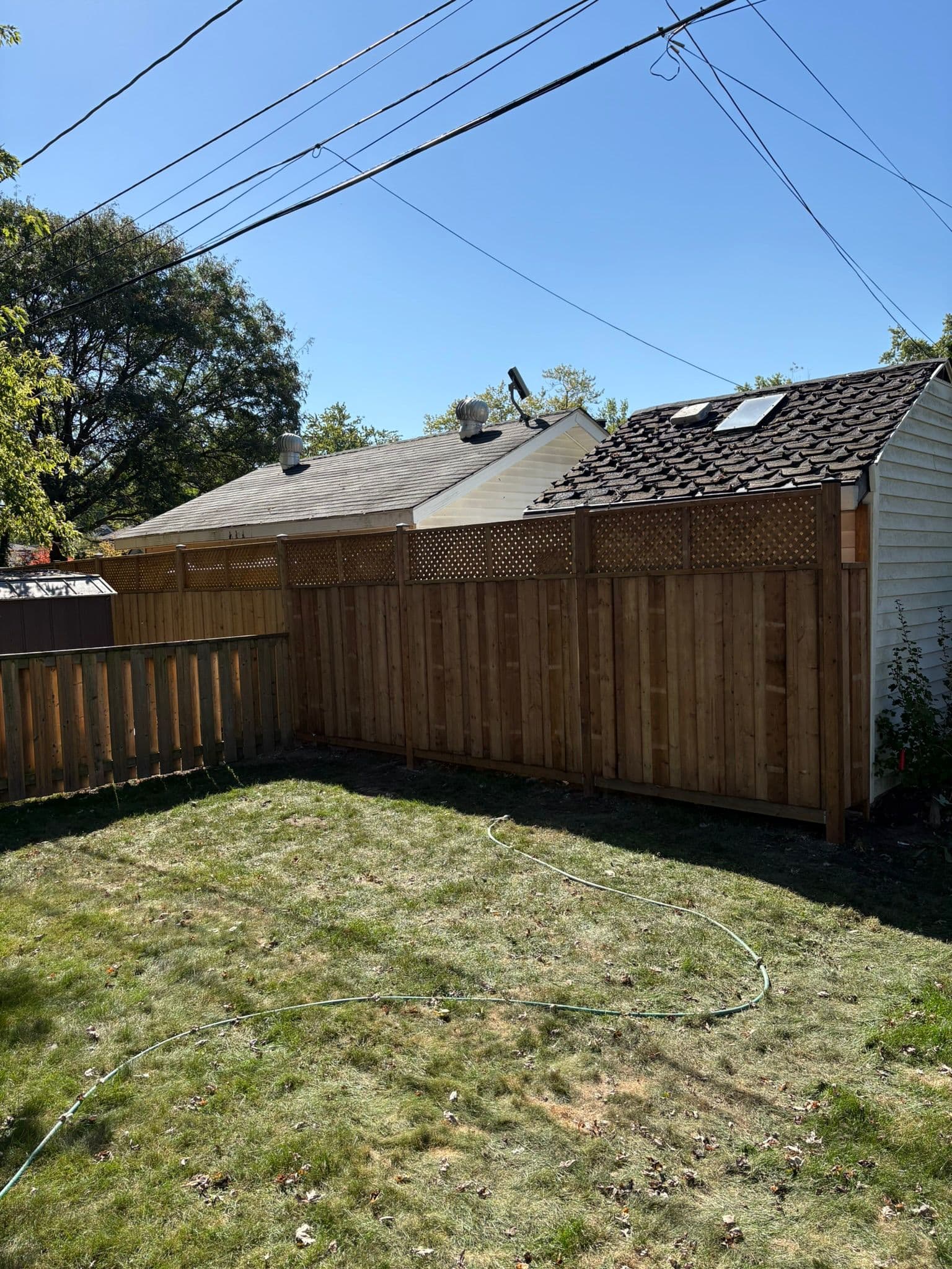 Horizontal wood slat fence installation along residential property