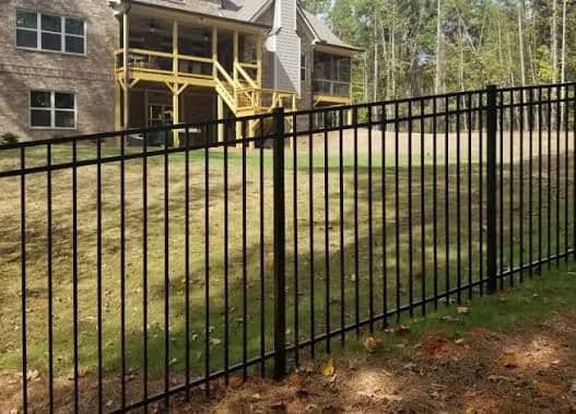Black aluminum picket fence installation next to brick home