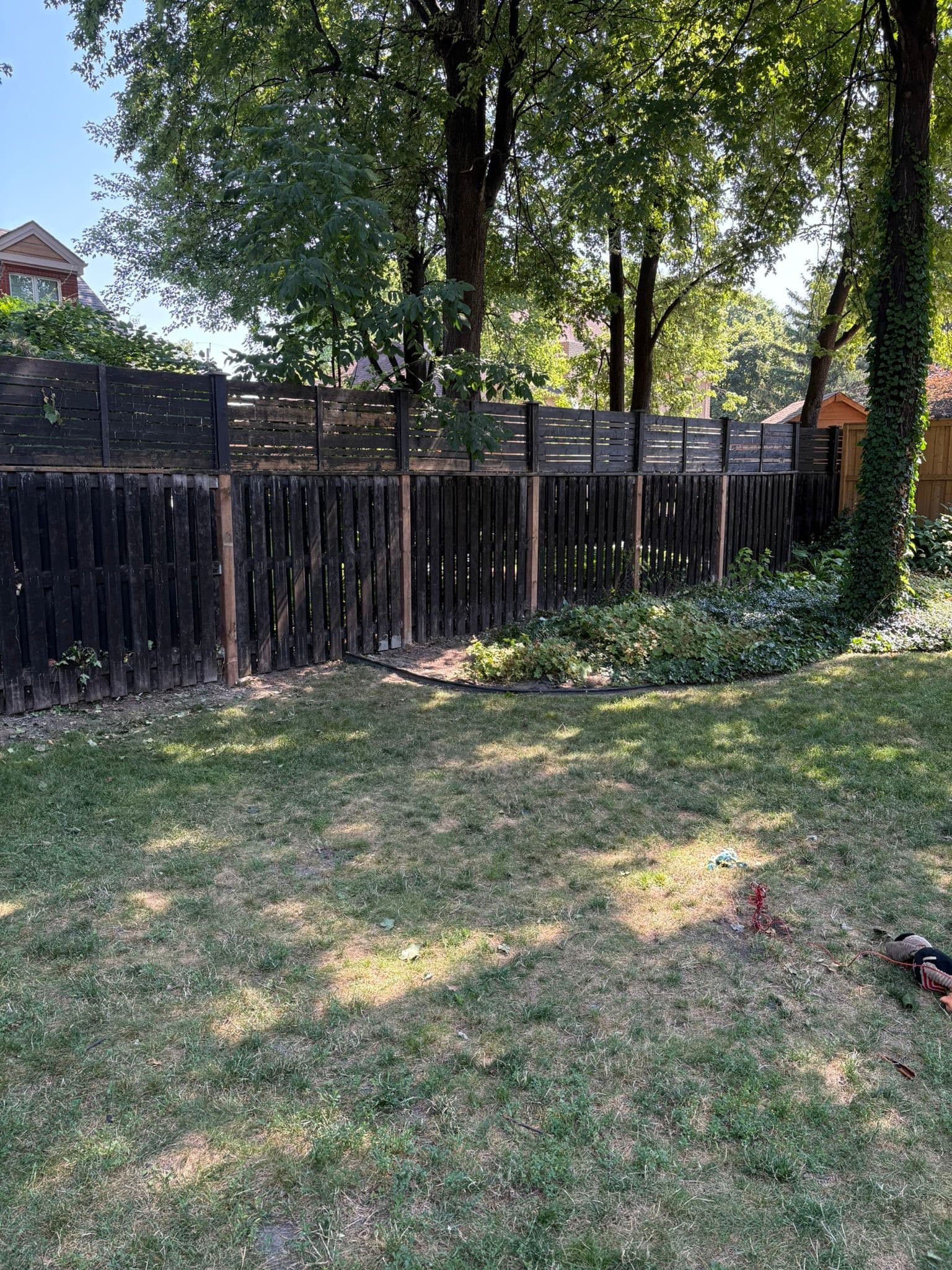 Weathered wood fence before repair in backyard